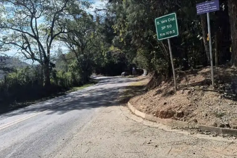 Estrada asfaltada com placa de identificação da via rural.